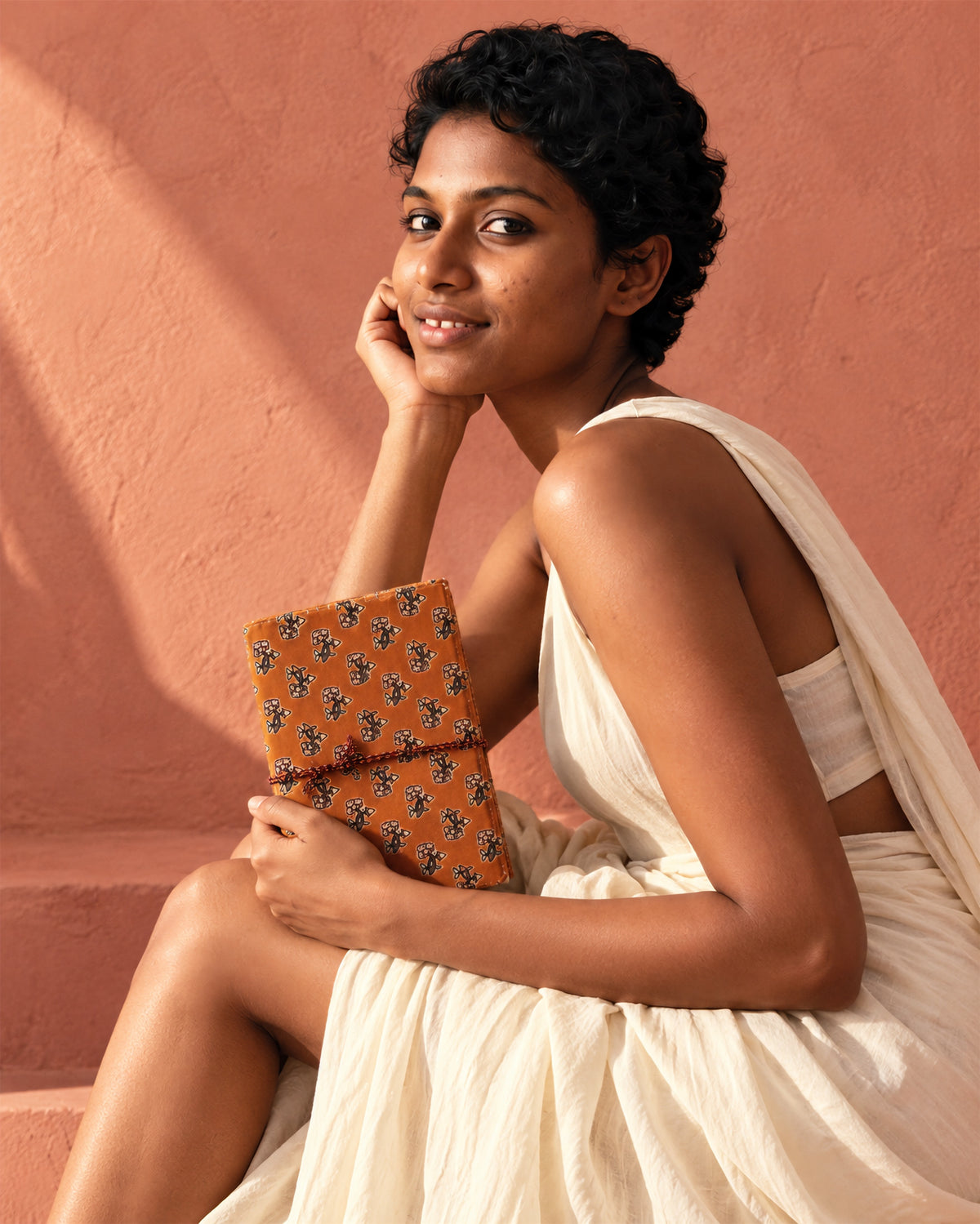 Amber Buti Block Print Fabric Diary, 200 Unruled Pages, held against a white dress, terracotta pink wall