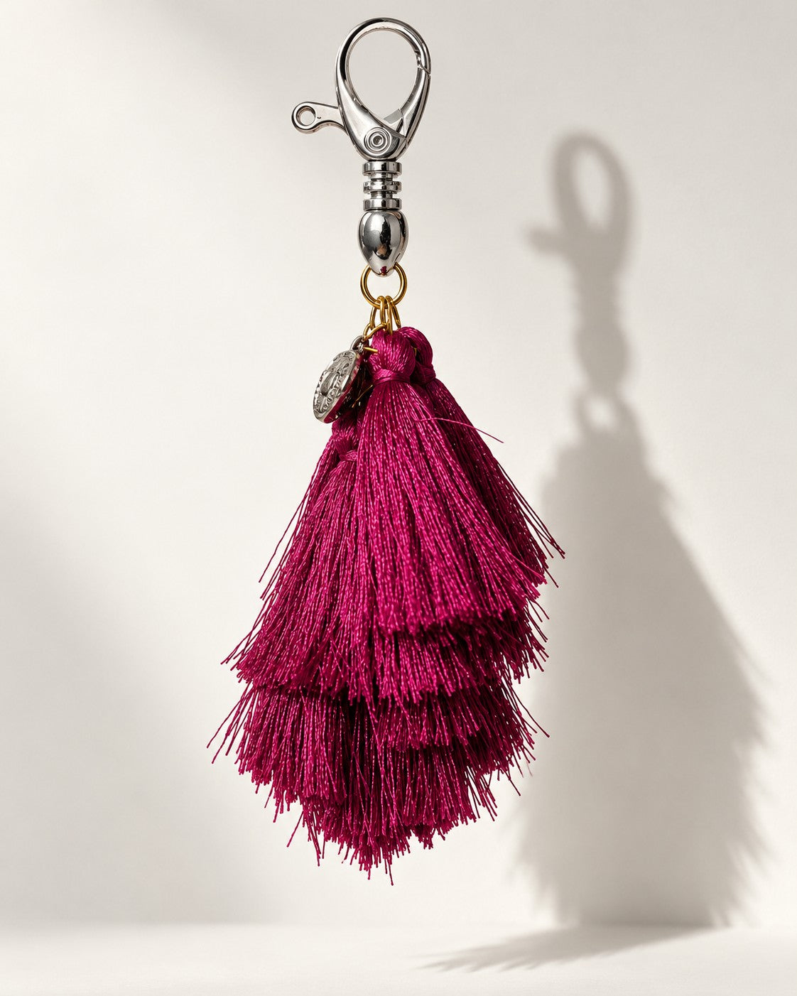 Jamuni silk tassel bag charm: one embossed silver-tone coin at the head, above tiered berry silk tassels. It hangs from a silver-tone swivel clasp.