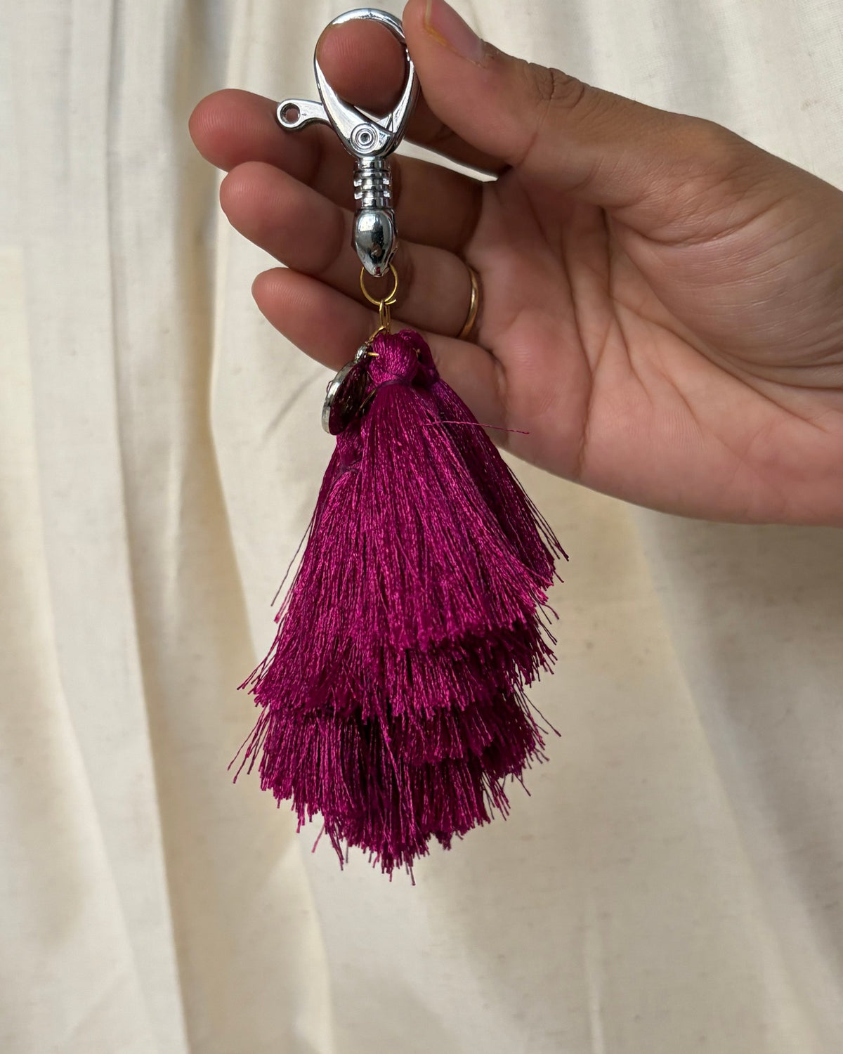 Jamuni silk tassel bag charm held in the hand to show its size, about 7¾ inches from clasp to fringe