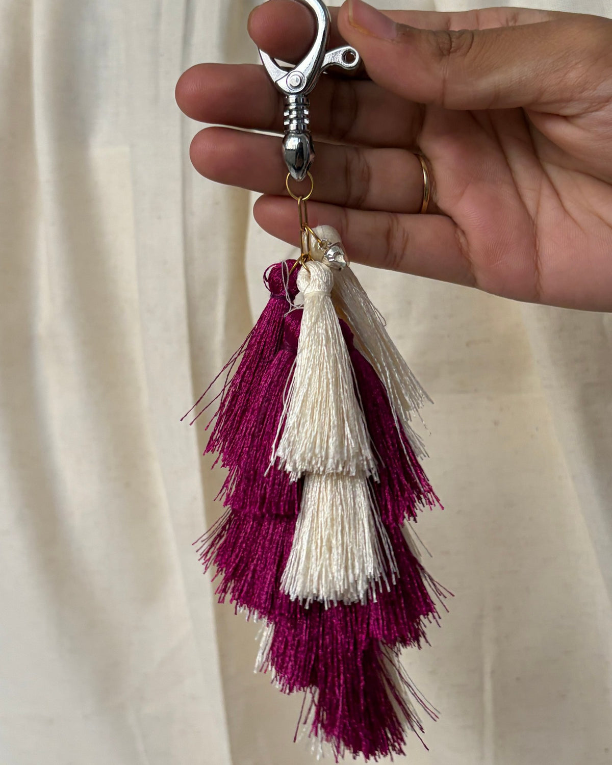 Aabha silk tassel bag charm held in the hand to show its size, about 9 inches from clasp to fringe