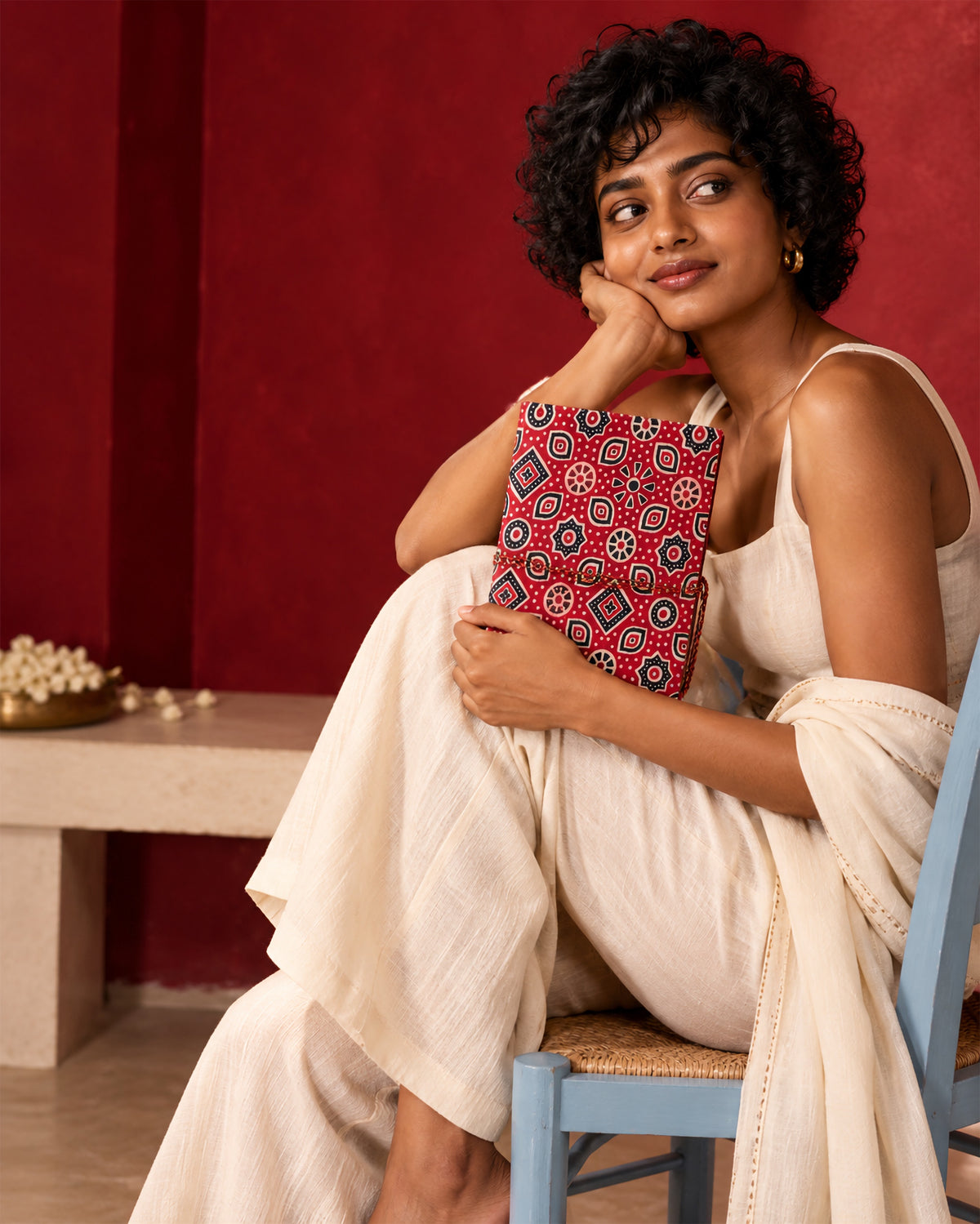 Crimson Ajrakh Block Print Fabric Diary, 200 Unruled Pages, held on the lap, white outfit, pale pink wall