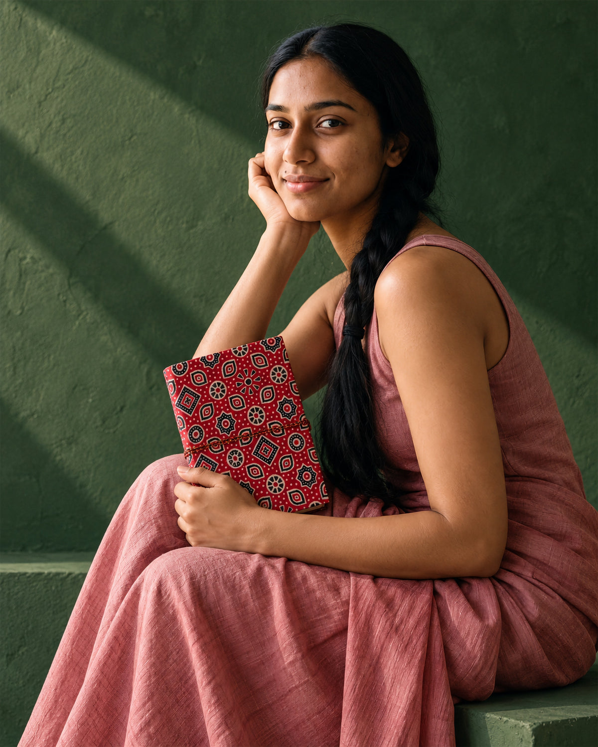 Crimson Ajrakh Block Print Fabric Diary, 200 Unruled Pages, held at the chest, pink dress, green wall