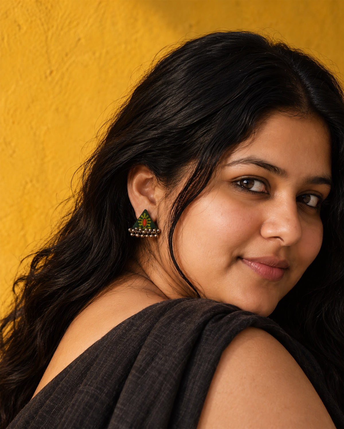 Riwaayat Morni Dark Green Triangle Earrings, worn, hair loose, dark grey top, saffron yellow wall