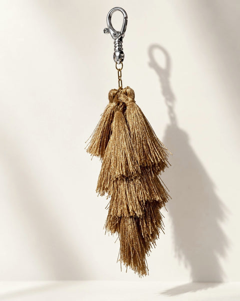 Zari silk tassel bag charm: a cluster of tiered antique-gold silk tassels on gold-tone chain links, with no ornament. It hangs from a silver-tone swivel clasp.