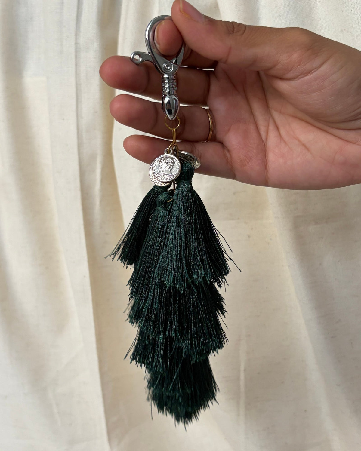 Neel Van silk tassel bag charm held in the hand to show its size, about 9 inches from clasp to fringe