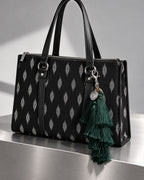 Neel Van silk tassel charm clipped to the Noor Black Ikat Laptop Tote Bag