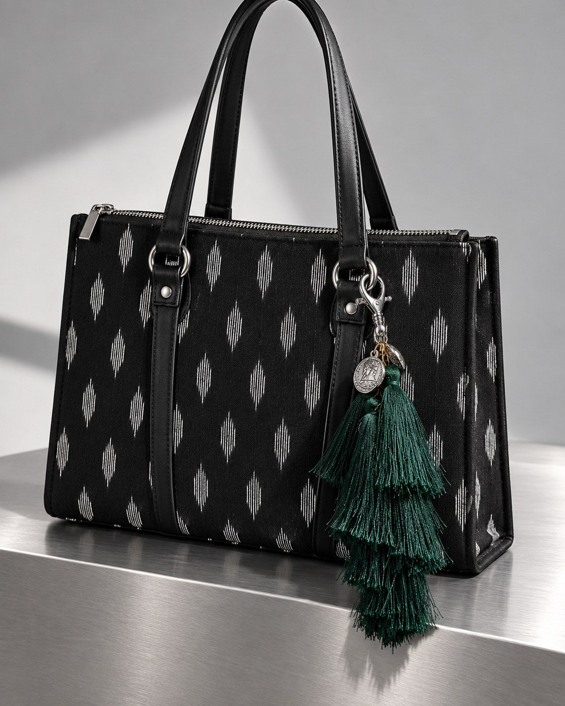 Neel Van silk tassel charm clipped to the Noor Black Ikat Laptop Tote Bag