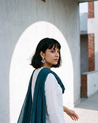 Teal Green Geometric Ghungroo Earrings worn with a white shirt and a teal cotton dupatta beside a whitewashed arch (AI-generated styling image)