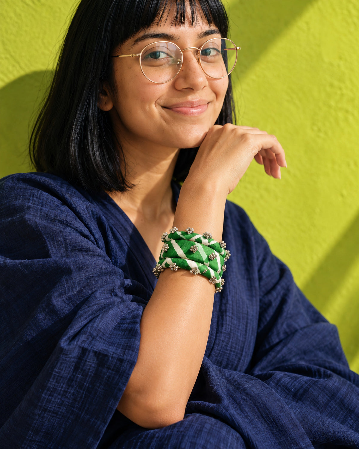 Lariya Green Leheriya Fabric Bangles with Ghungroo, Kada Set of 3, worn on the wrist, hand at the chin, navy dress, chartreuse wall