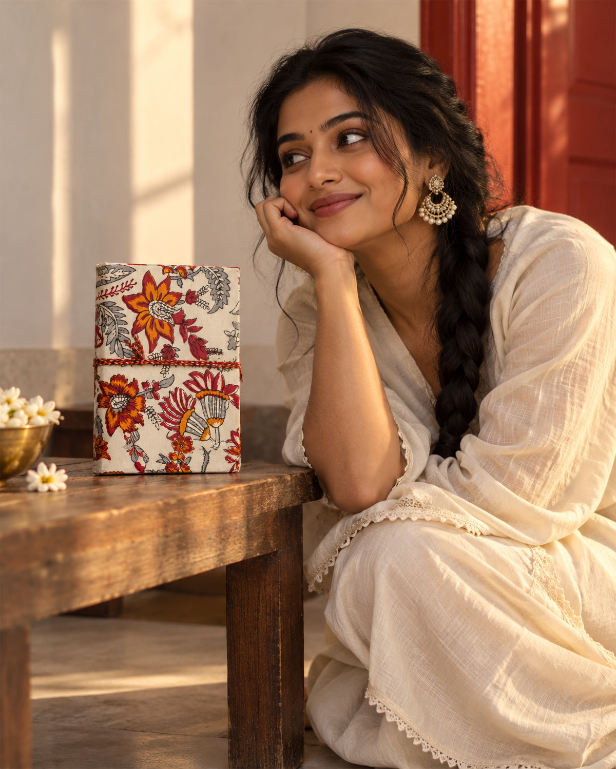 Hara Mahal Block Print Fabric Diary, 200 Unruled Pages, resting on a wooden table, braid over the shoulder, white kurta