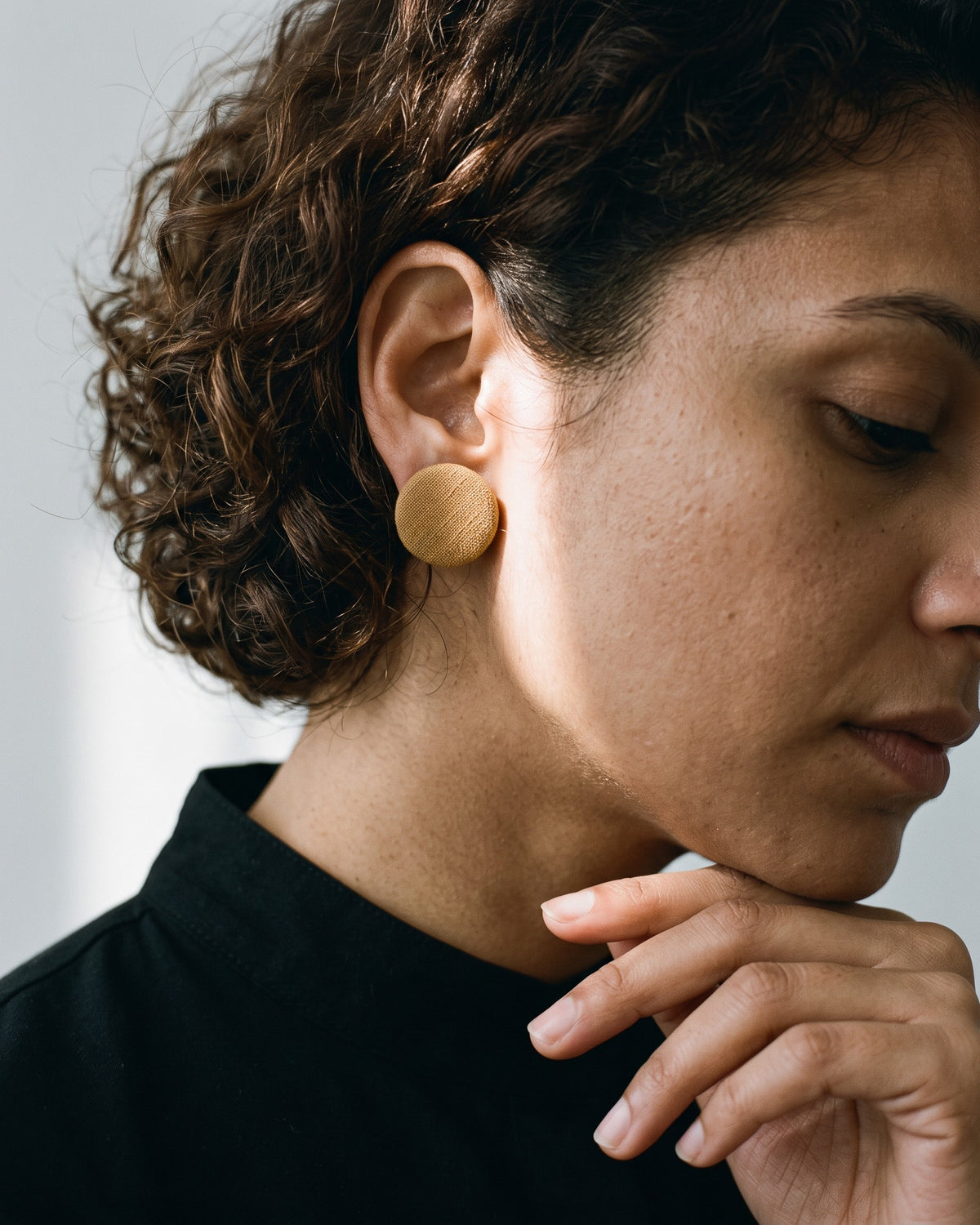 Ibrik Accents Fabric Stud Earrings worn on a model in a black high neck, bone-white studio (AI-generated styling image)