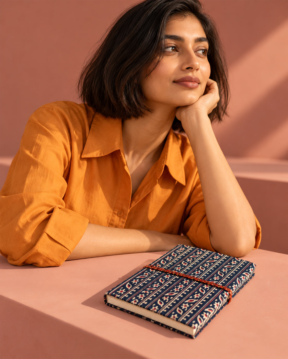 Indigo Ajrakh Block Print Fabric Diary, 200 Unruled Pages, lying flat on a table, orange shirt, terracotta wall