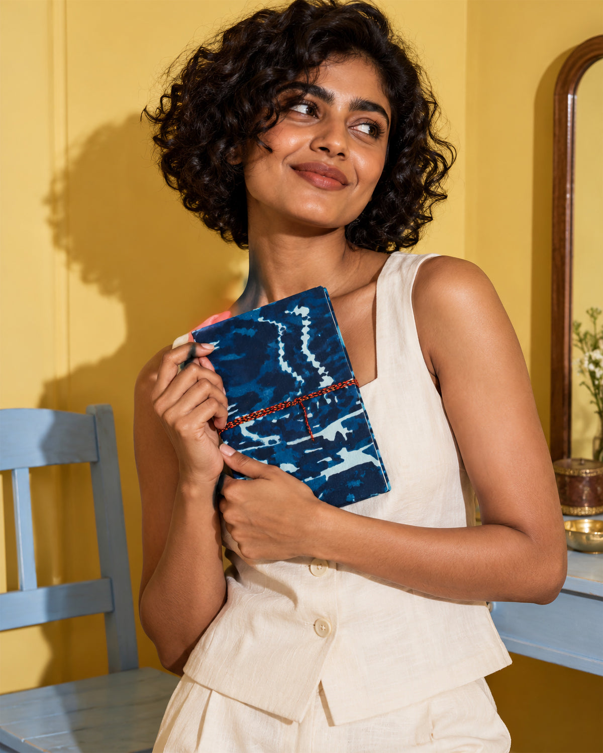 Indigo Shibori Block Print Fabric Diary, 200 Unruled Pages, held in both hands, white top, yellow wall