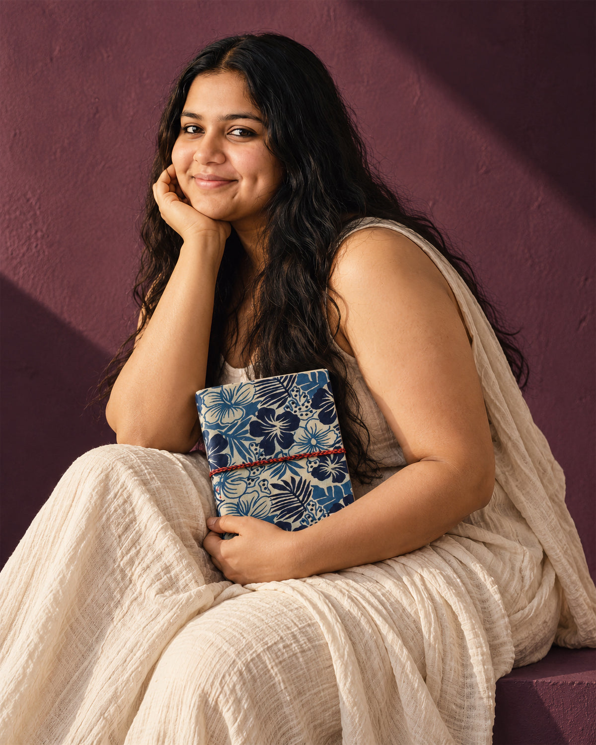 Indigo Tropics Block Print Fabric Diary, 200 Unruled Pages, held at the chest, white dress, aubergine wall