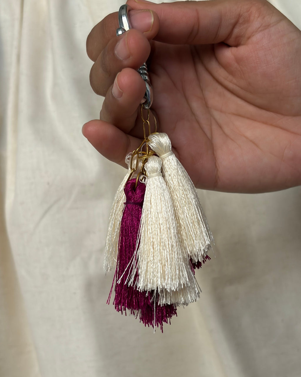 Gulal silk tassel bag charm held in the hand to show its size, about 6¾ inches from clasp to fringe