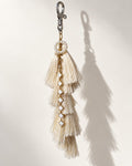 Motiya silk tassel bag charm: a small ring of white pearl beads at the head and a gold-tone chain of white clover links running down the front. It hangs from a silver-tone swivel clasp.