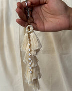 Motiya silk tassel bag charm held in the hand to show its size, about 9 inches from clasp to fringe