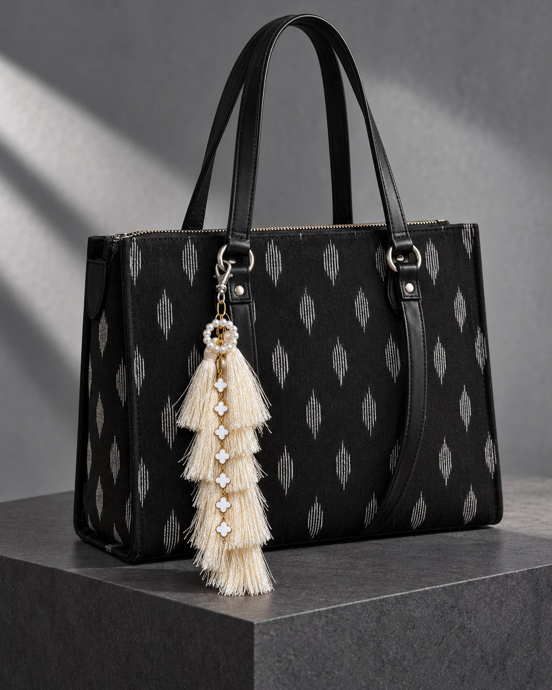 Motiya silk tassel charm clipped to the Noor Black Ikat Laptop Tote Bag