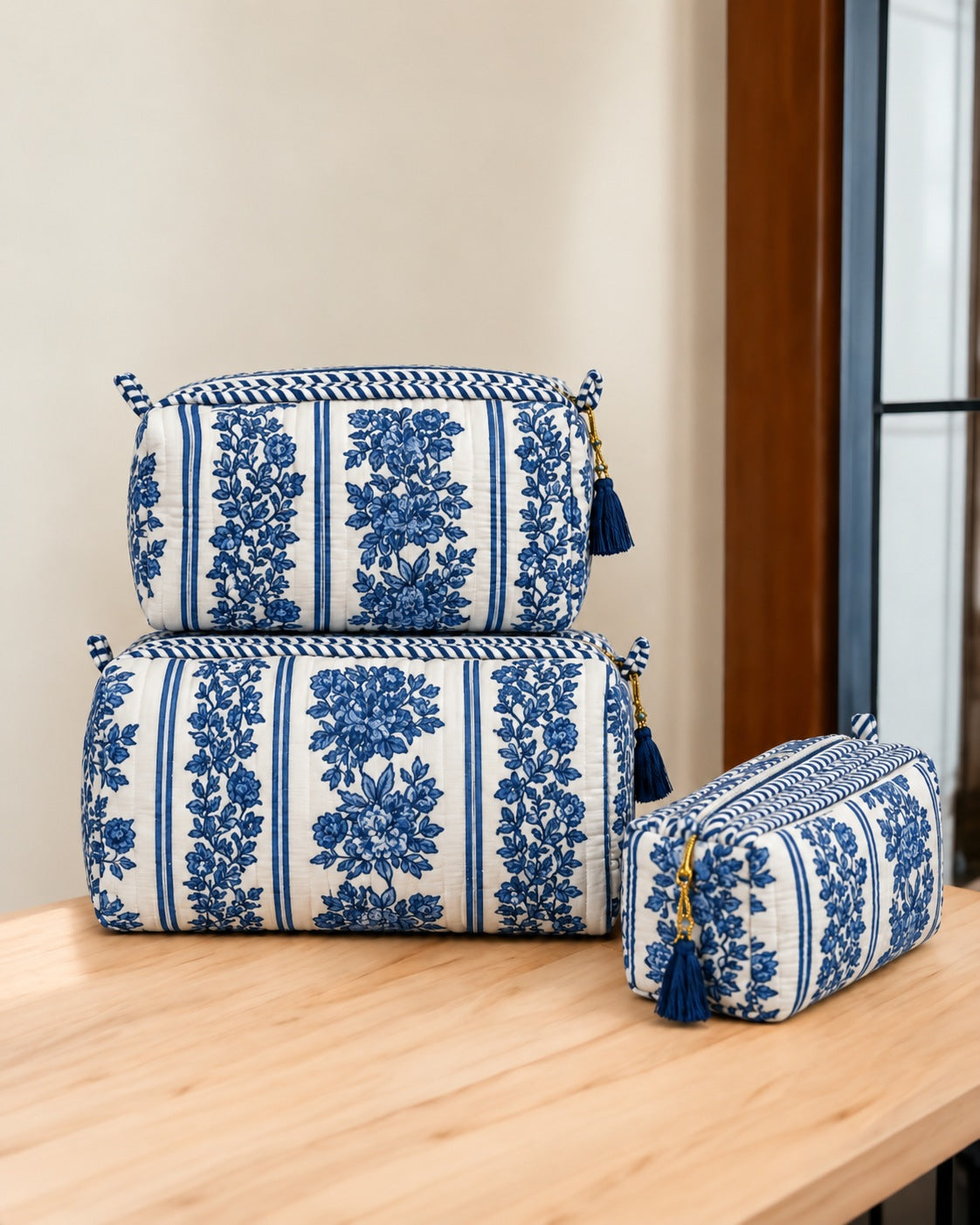 Jharna blue floral quilted pouches stacked, with blue tassels on the gold-tone zip pulls