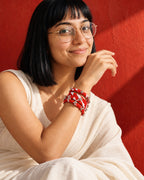 Lariya Red Leheriya Fabric Bangles with Ghungroo, Kada Set of 3, worn stacked on the wrist, hand at the cheek, white kurta, terracotta pink wall