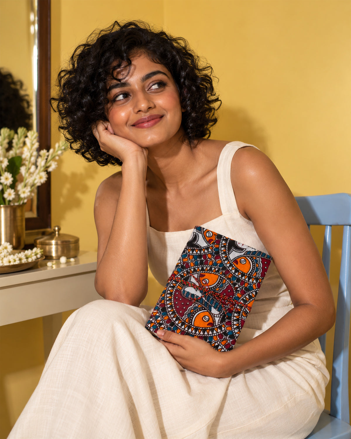 Madhubani Carnival Block Print Fabric Diary, 200 Unruled Pages, held at the chest, white top, pale yellow wall