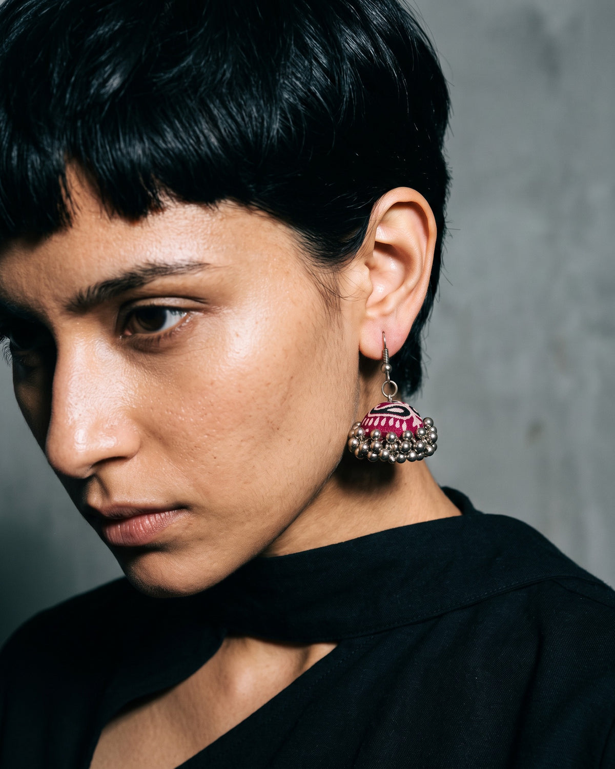 Marigold Zigzag Jhumka Earrings worn on a model with a blunt fringe, grey studio (AI-generated styling image)