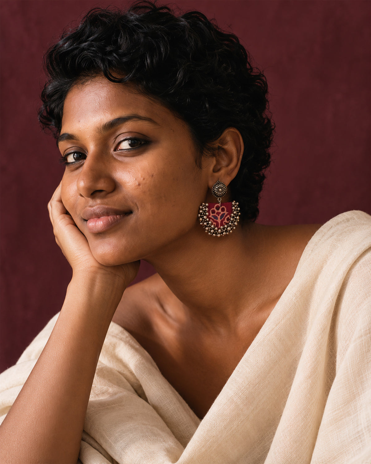 Maroon Chandbali Earrings with Ghungroo, worn, hand at the cheek, cream top, maroon wall