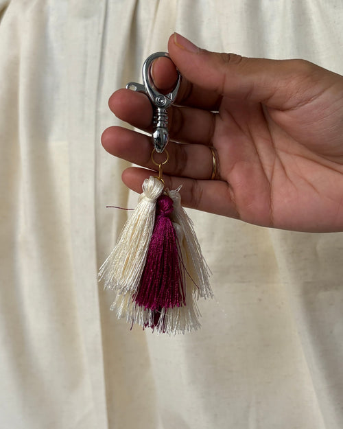 Abeer silk tassel bag charm held in the hand to show its size, about 6¼ inches from clasp to fringe