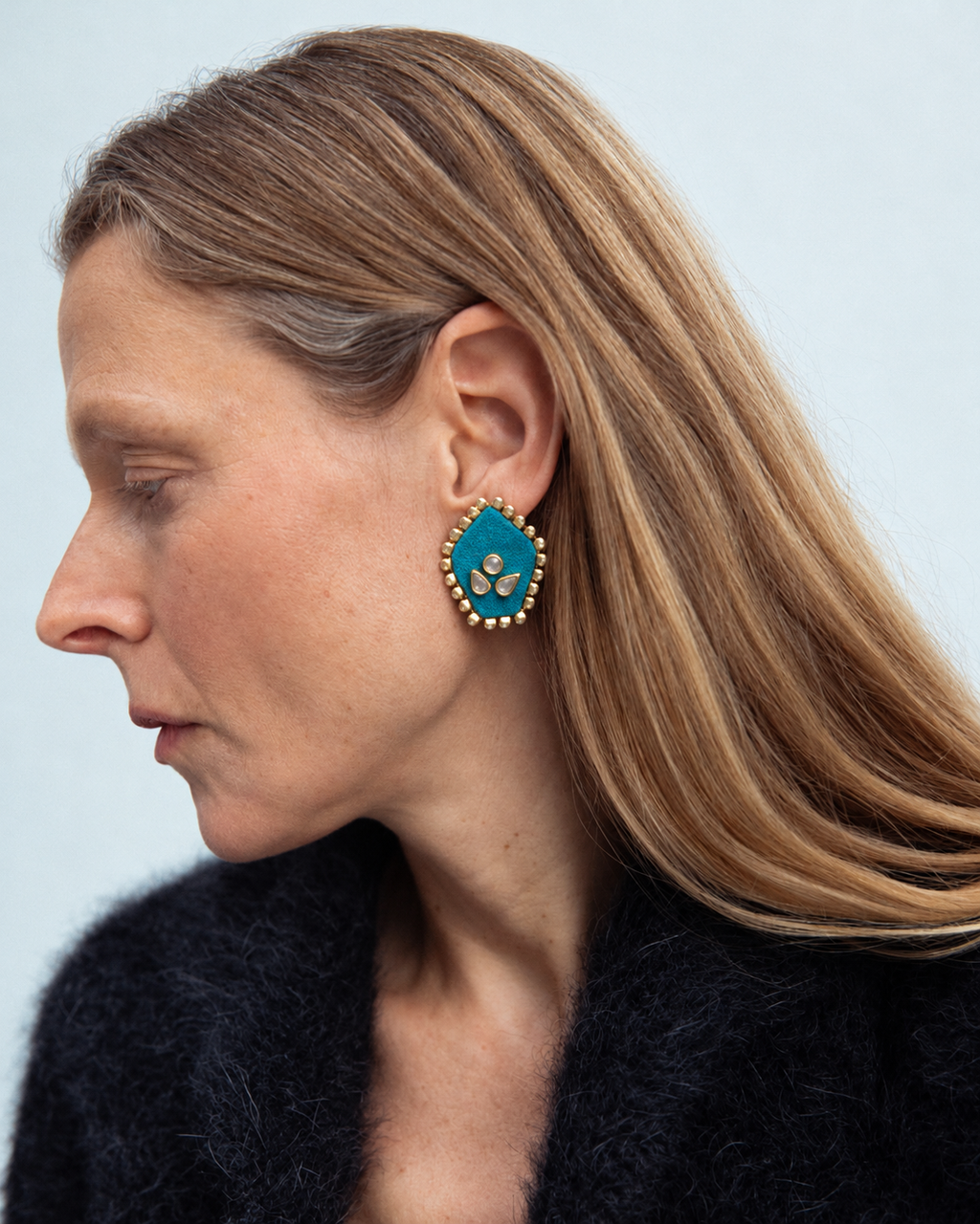 Firozi pentagon kundan stud earring worn with a black knit, seen in profile
