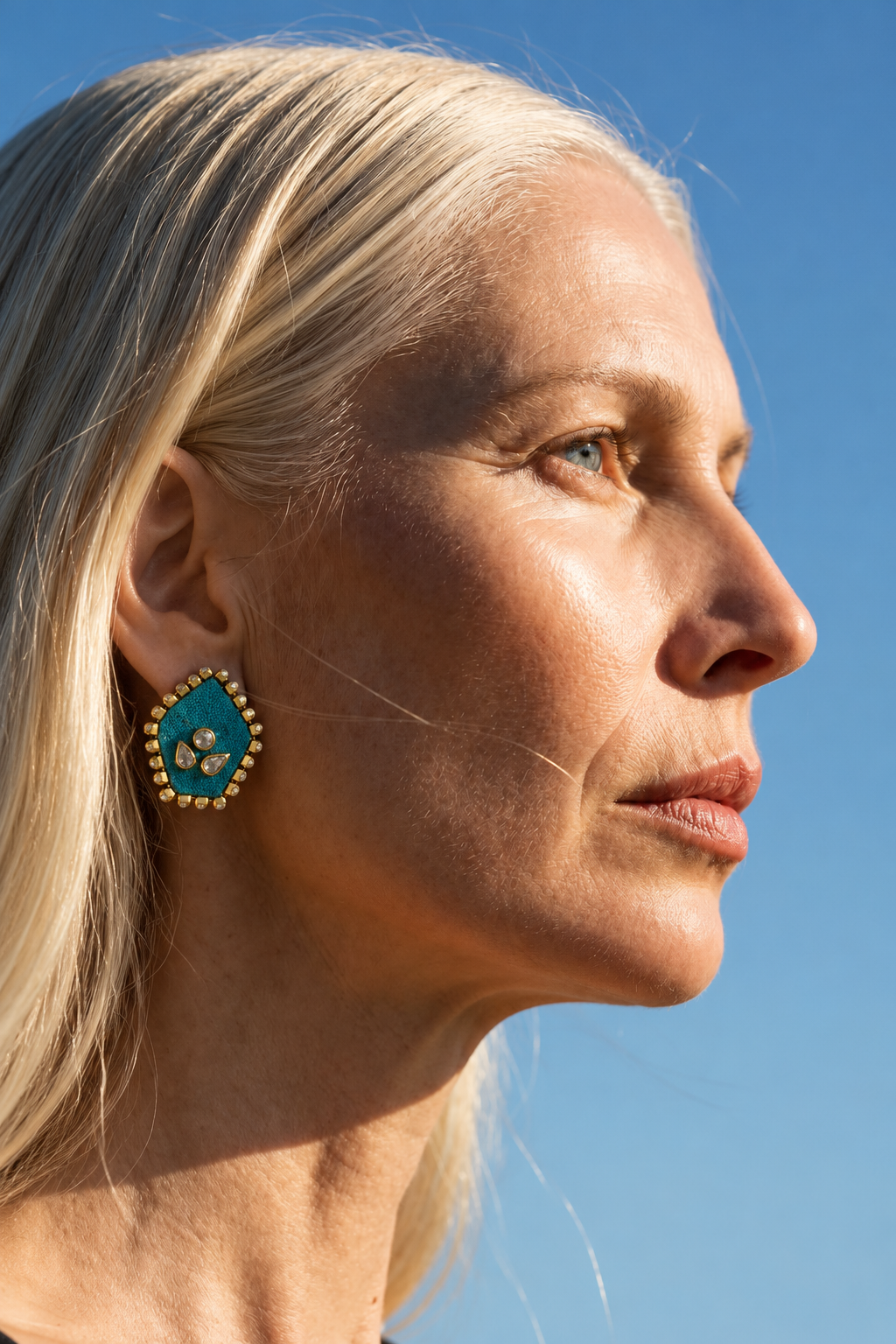 Mogra Firozi Pentagon Kundan Stud in profile against a blue sky: a turquoise blue five-sided fabric centre with three kundan stones and a border of small kundan