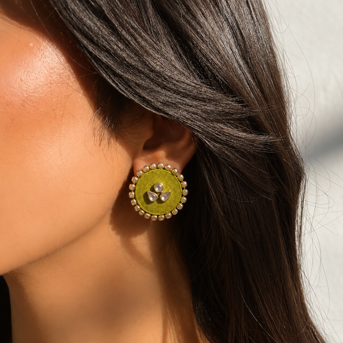 Mogra Lime Green Round Kundan Studs close to the ear: one round and two pear-shaped kundan stones on a lime green fabric centre, edged with small kundan