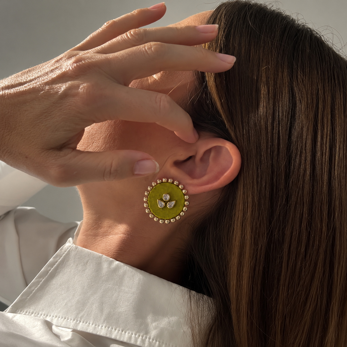 Mogra Lime Green Round Kundan Studs worn on the ear as she tucks her hair back: a lime green fabric centre with three kundan stones and a border of small kundan