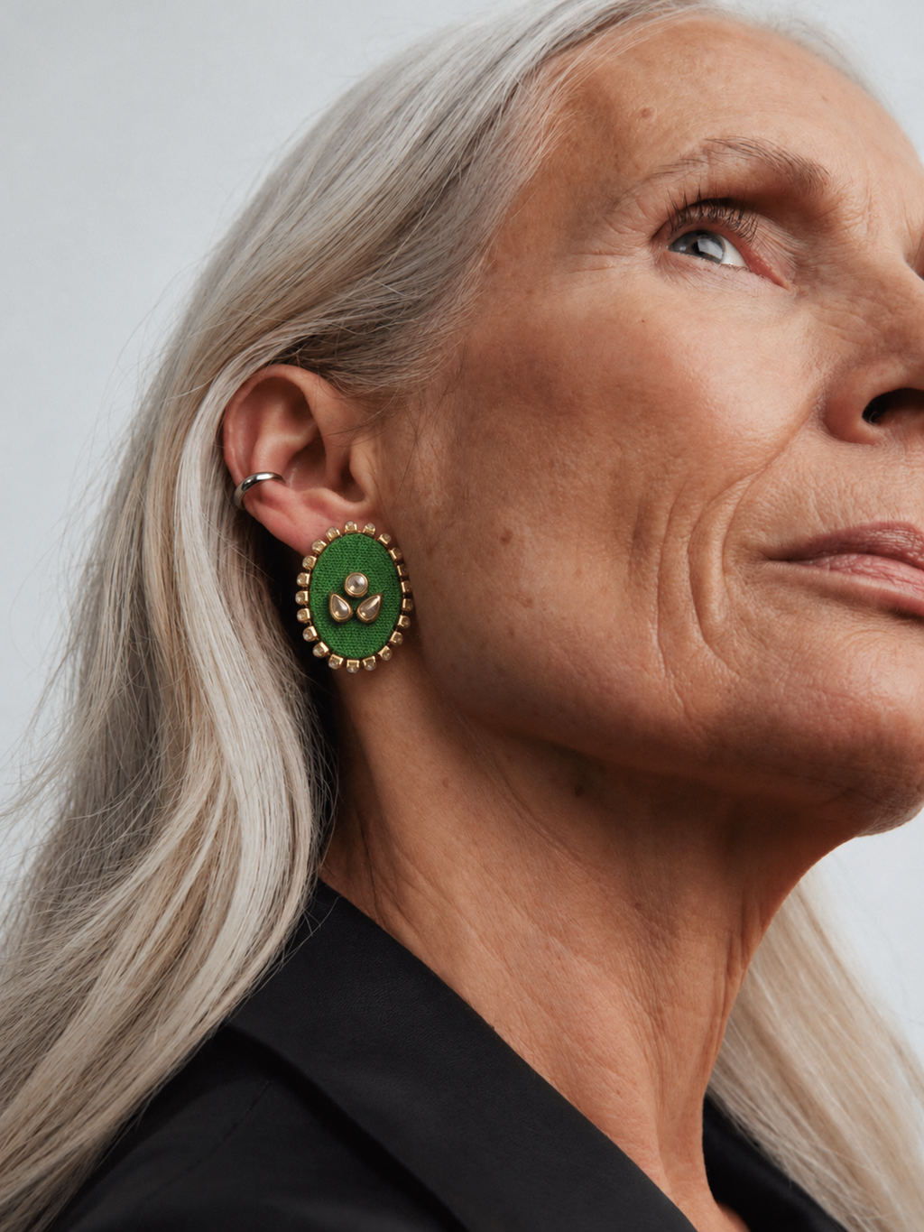 Parrot green oval kundan stud earring seen up close in profile with long silver hair