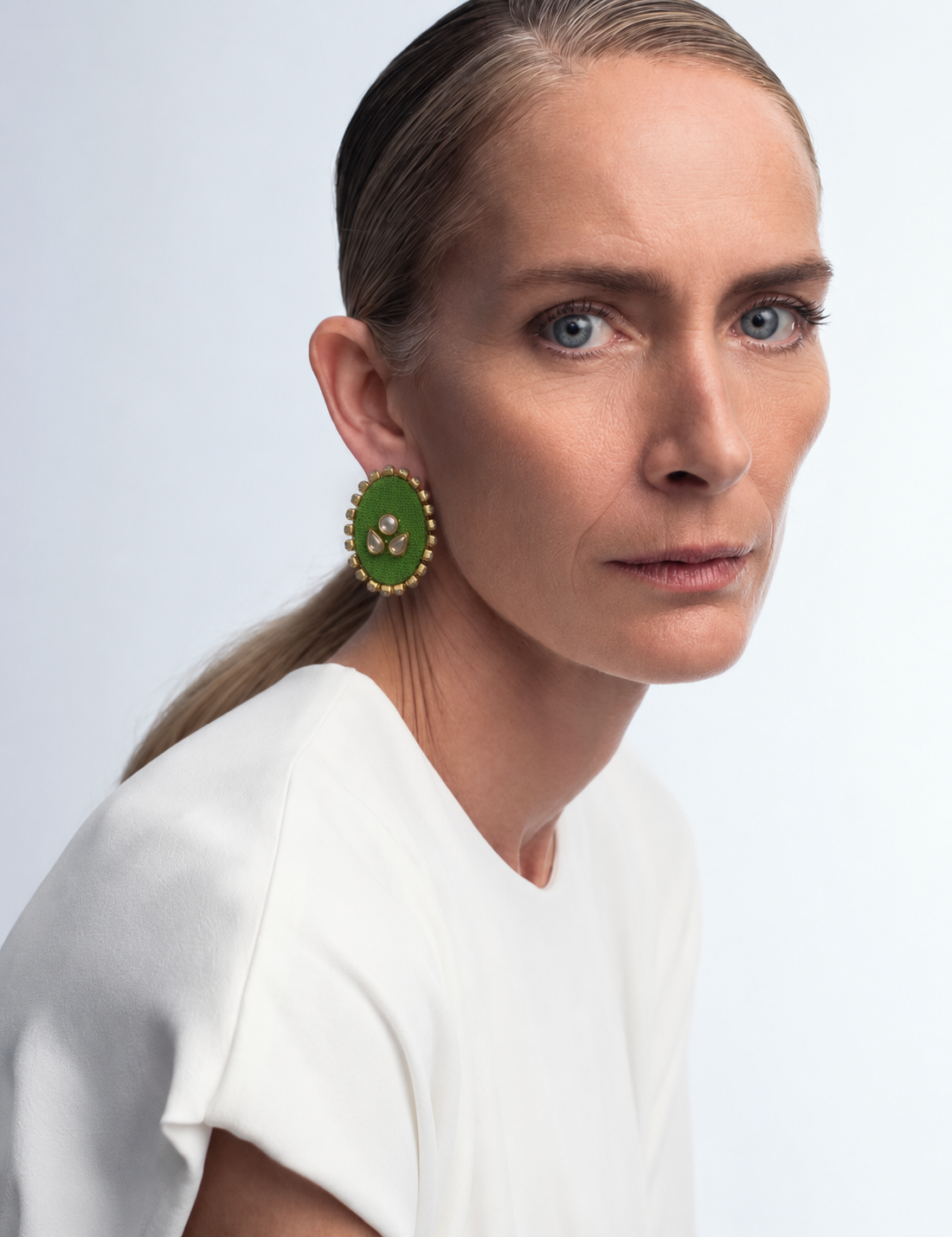 Mogra parrot green oval kundan stud worn with a white T-shirt and hair pulled back