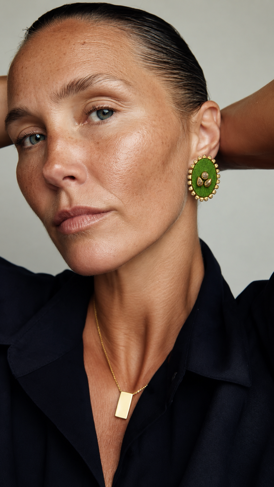 Mogra Parrot Green Oval Kundan Stud worn with a black shirt and a gold pendant: a leafy green oval fabric centre, three kundan stones and a small kundan border