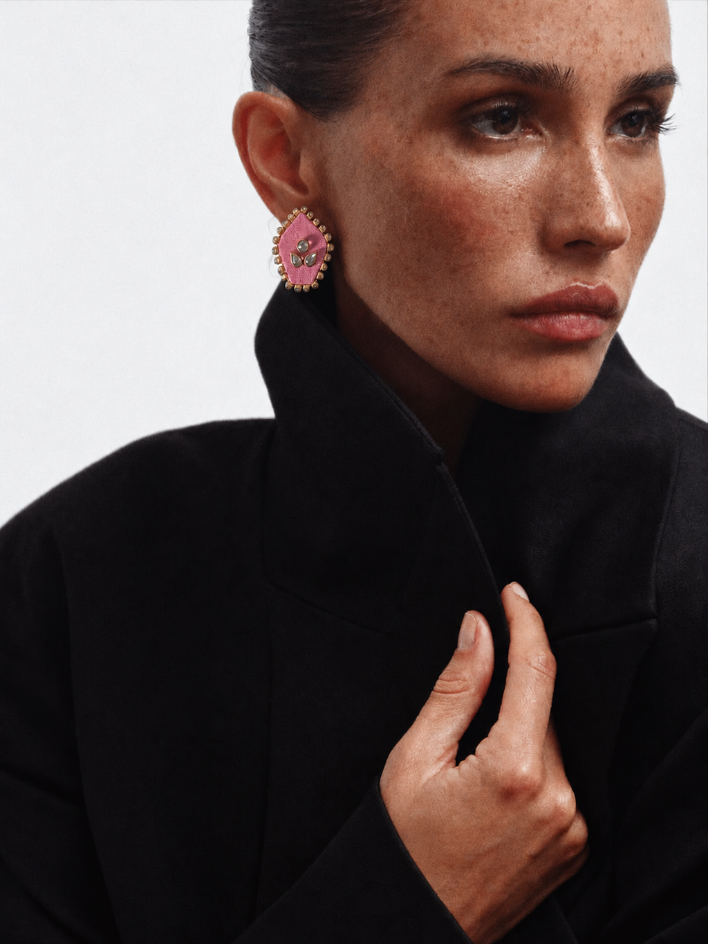 Pink pentagon kundan stud earring worn with a black coat, collar up
