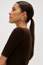 Mogra Pink Pentagon Kundan Stud in profile with a brown knit and a long ponytail: a soft pink five-sided fabric centre with three kundan stones and a small kundan border