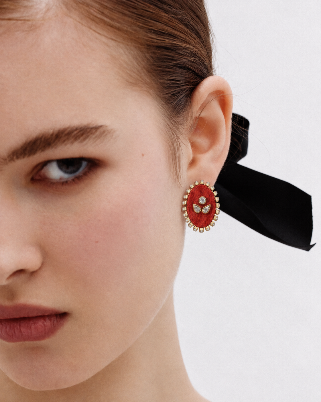 Close-up of the Mogra red oval kundan stud with a black ribbon in the hair