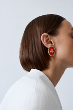 Red oval kundan stud earring in profile with a sleek bob and a white shirt