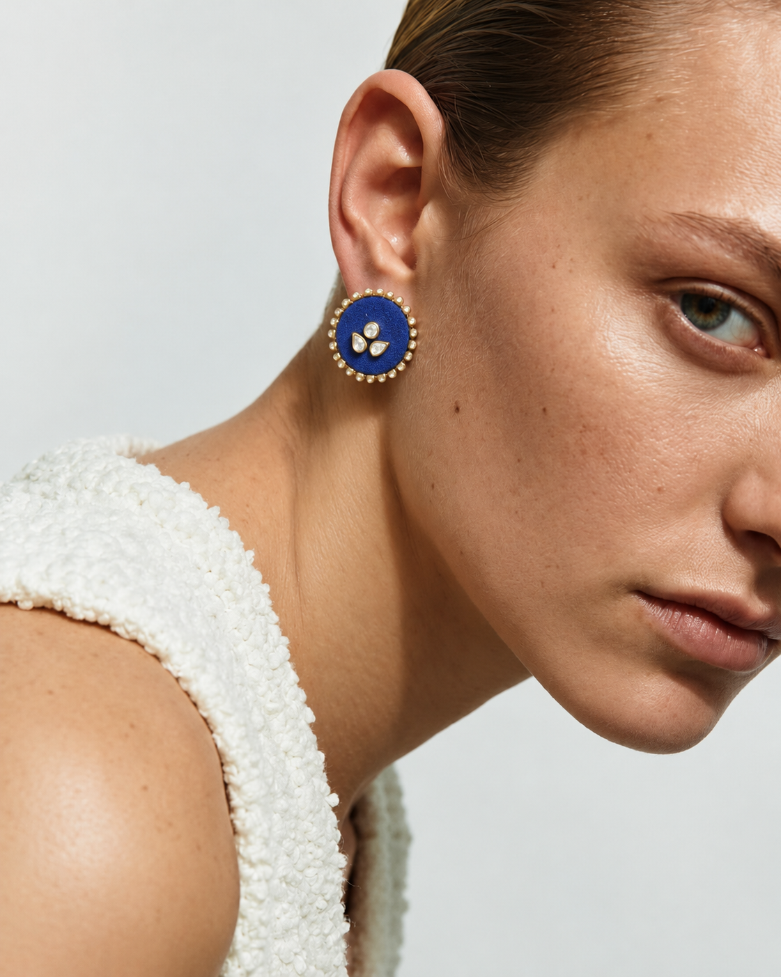 Royal blue round kundan stud earring seen up close with a white textured top
