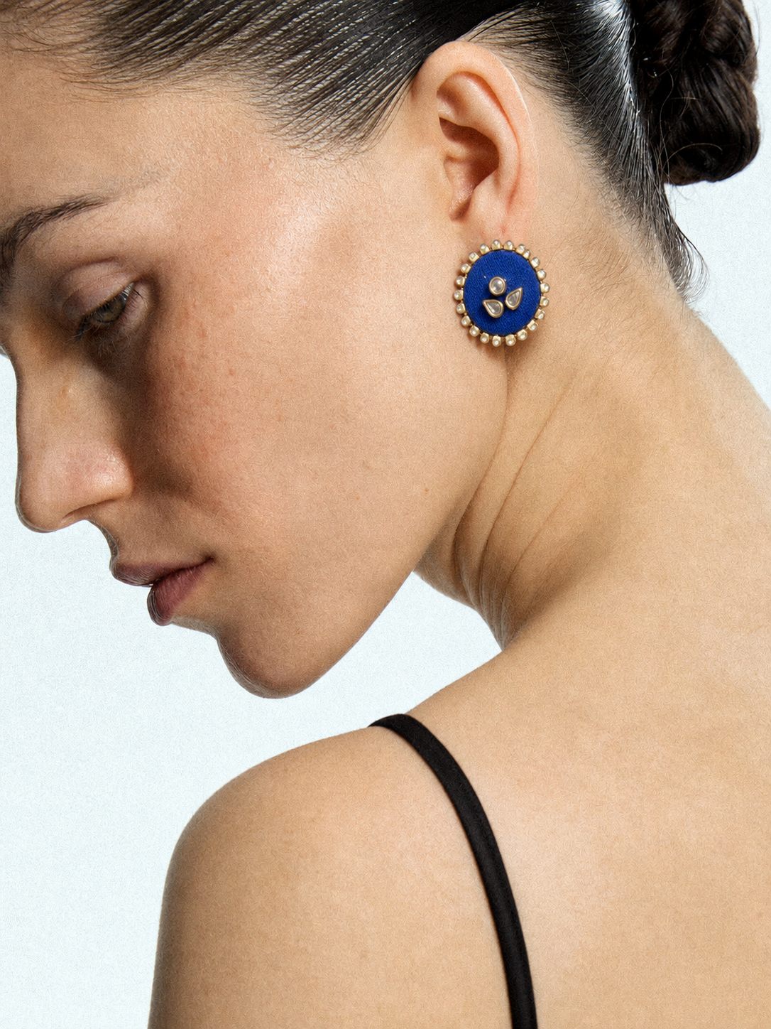 Mogra Royal Blue Round Kundan Studs in profile with a black strap top: three kundan stones on royal blue fabric ringed with small kundan
