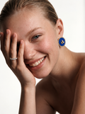 Mogra Royal Blue Round Kundan Stud worn by a smiling model with her hand to her cheek: royal blue fabric centre, three kundan stones, small kundan border