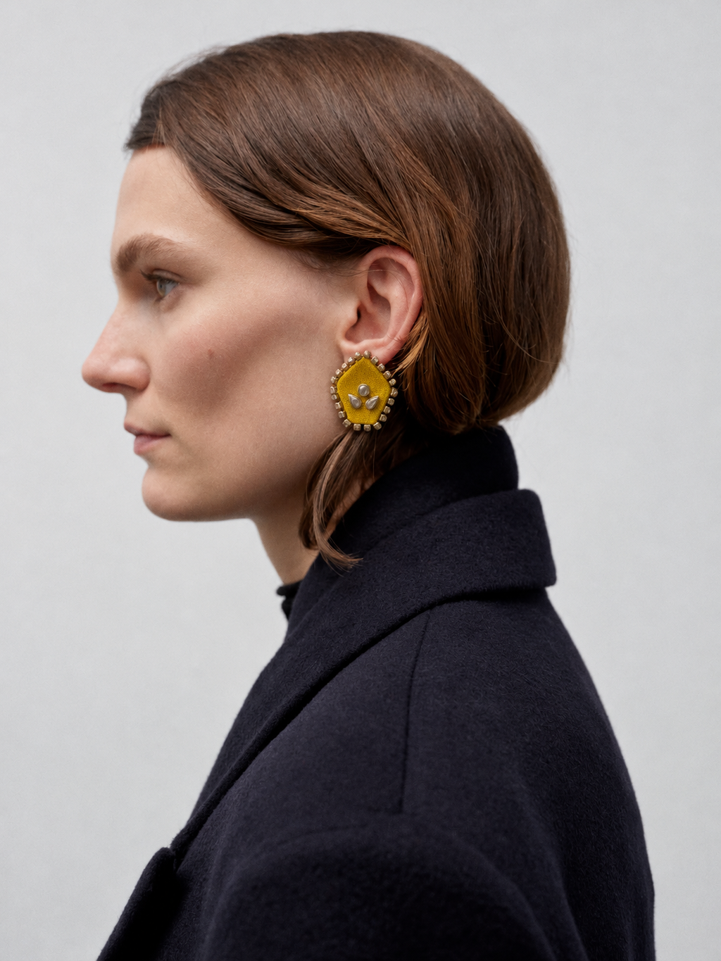Mogra yellow pentagon kundan stud in profile with a black coat