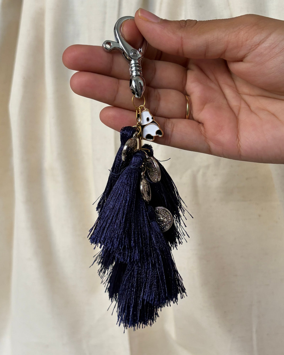 Nisha silk tassel bag charm held in the hand to show its size, about 9 inches from clasp to fringe