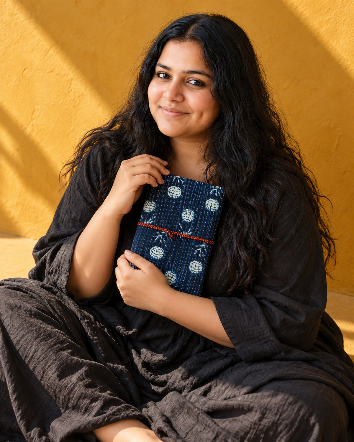 Navy Geometric Block Print Fabric Diary, 200 Unruled Pages, held at the chest, black outfit, yellow wall