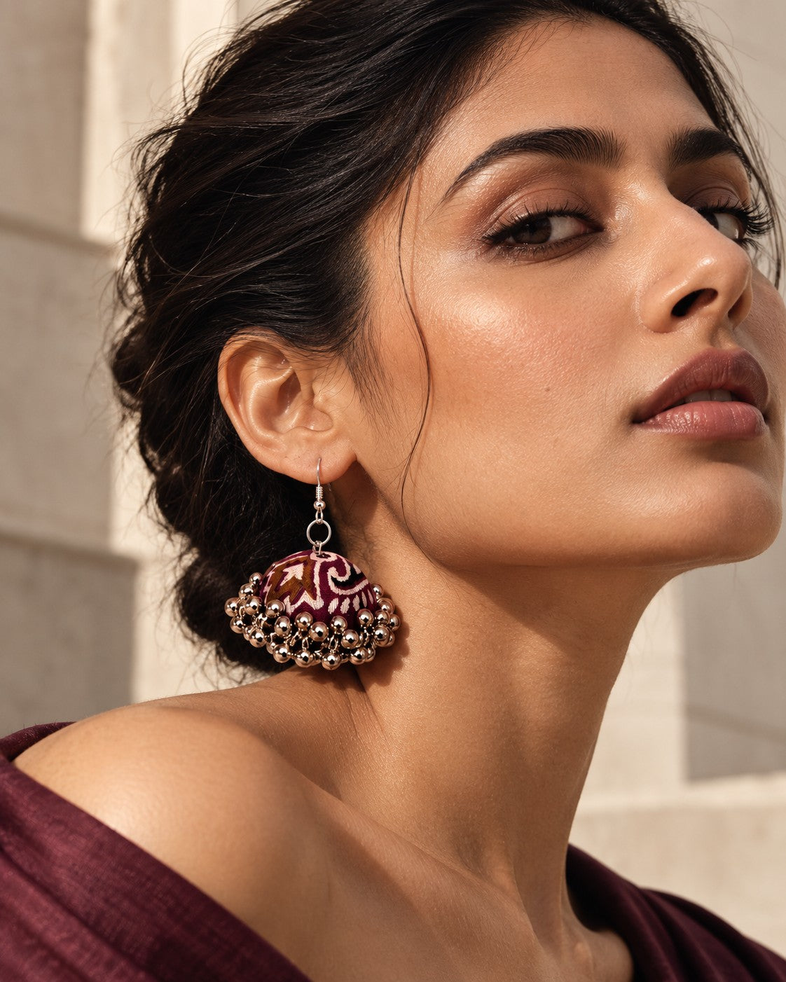 Neel Kamal Jhumka Earrings worn on a model against a sandstone wall (AI-generated styling image)