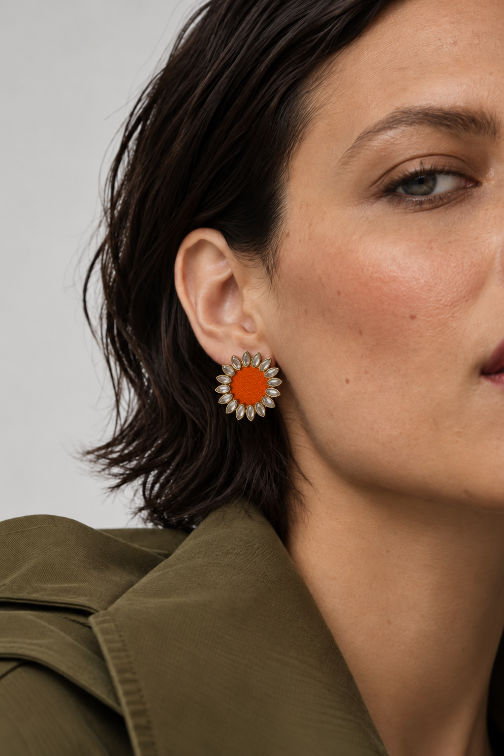 Orange Floral Kundan Earrings with an olive trench coat and a short bob: a small kundan sunflower with an orange fabric centre