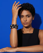 Black floral fabric bangles worn with a black top against a blue backdrop