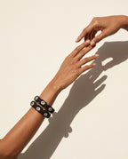 Black printed fabric bangles on the wrist against an ivory wall
