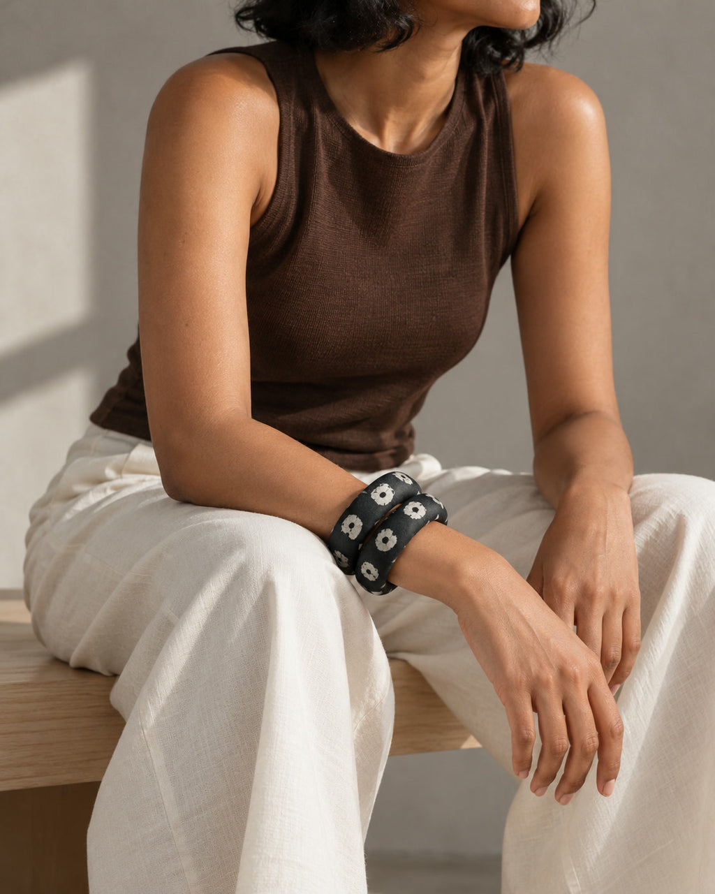 Dark green fabric bangles worn with a brown top and ivory trousers